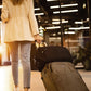Black travel bag with front zip pocket and padded shoulder strap.