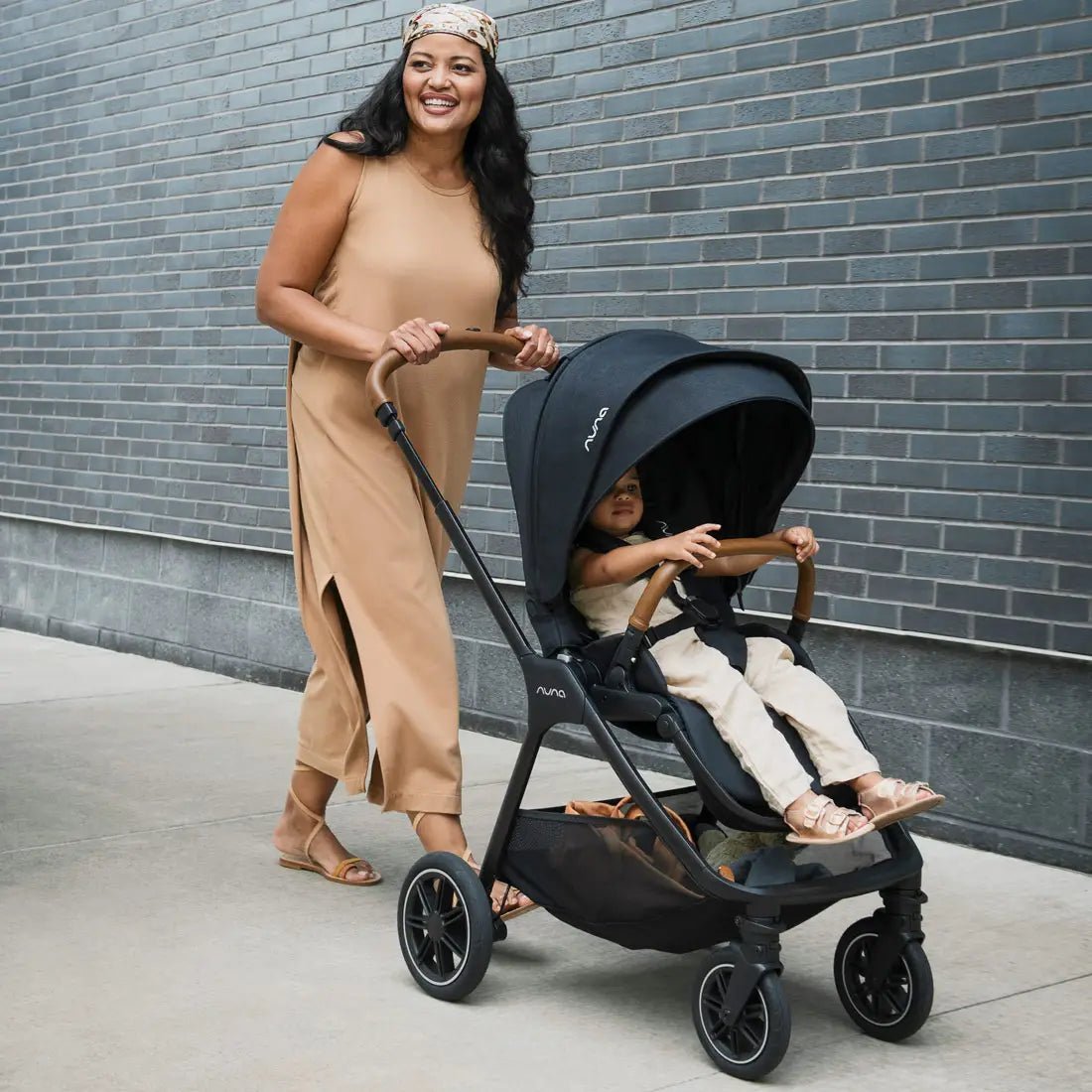 Black stroller with canopy and toddler seat, wheels and handlebar visible