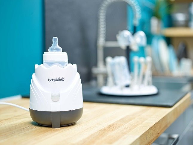 babymoov cream bottle steam warmer on a table with dark base