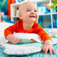Baby smiling in orange shirt on teal and white activity mat with crinkle edges