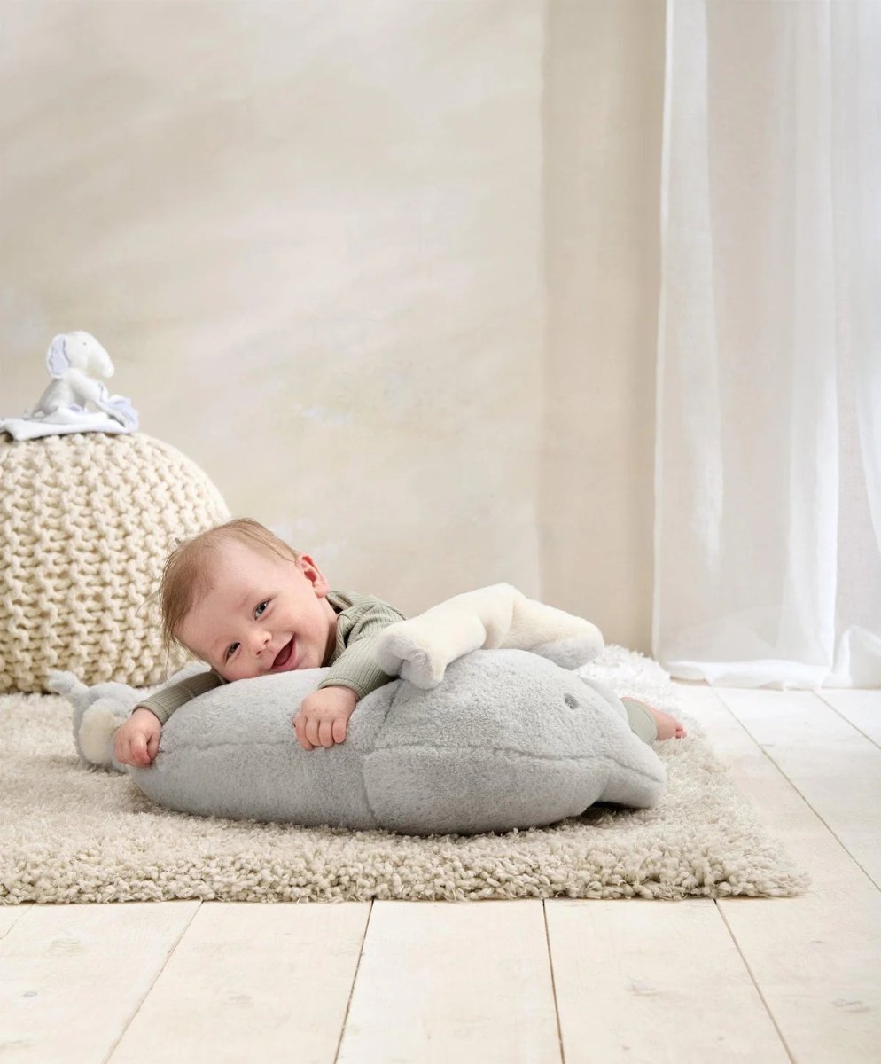 Elephant tummy time cushion rug in light gray with cream ear accents, with baby lying