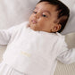 White velour baby bib worn by infant, front logo label visible