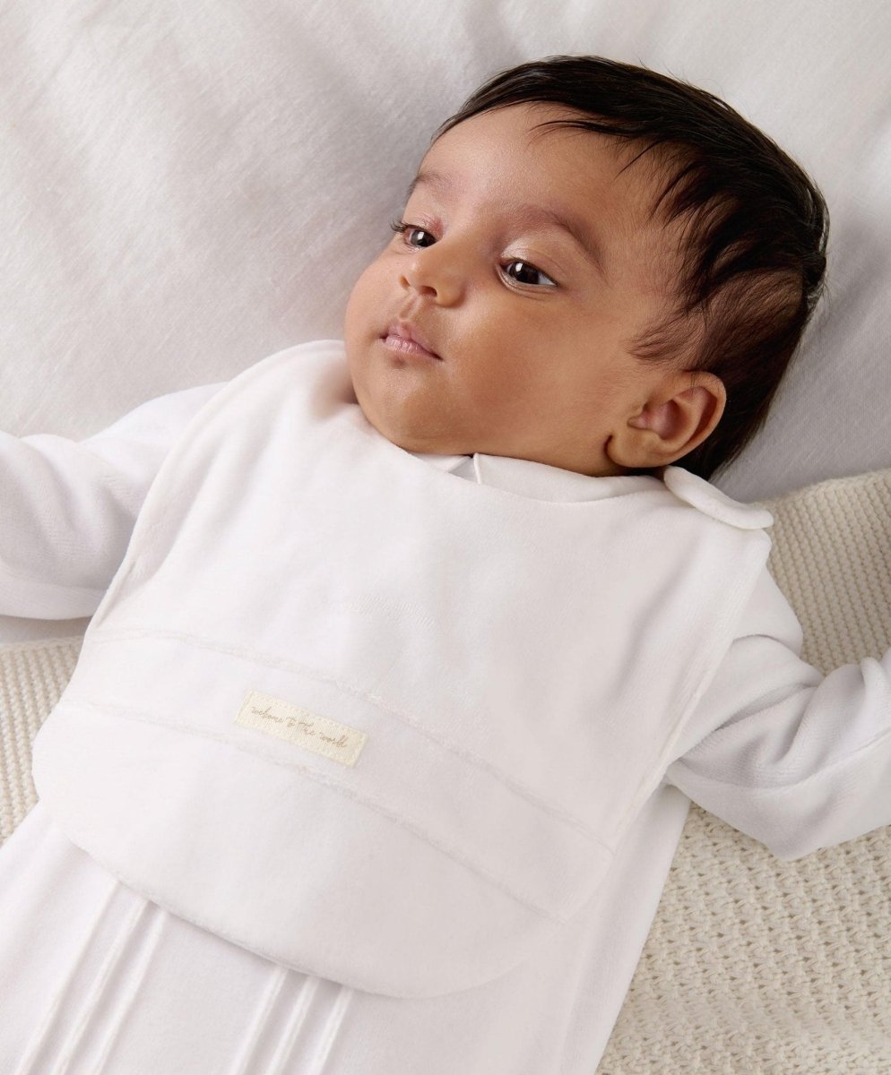 White velour baby bib worn by infant, front logo label visible