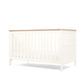 White cotbed angled side view with vertical slats and panel ends