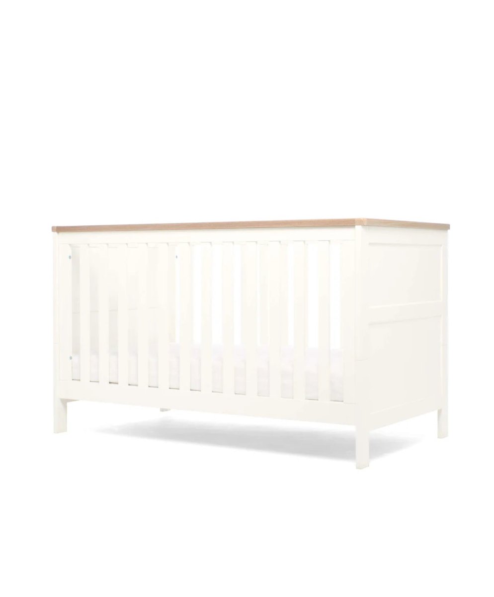 White cotbed angled side view with vertical slats and panel ends