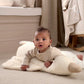 Baby on a light cream plush tummy time duck, belly-down on the padded support.