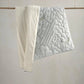 Cotbed quilt with raised cloud quilt pattern in light gray