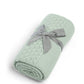 Mint green knitted blanket, rolled and tied with a gray fabric band
