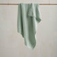 Knitted blanket in mint green with textured waffle pattern, draped over a display