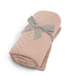 Seedling knitted blanket in dusty pink, folded with gray bow ribbon at center