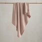 Seedling knitted blanket in dusty pink with textured waffle knit, folded and draped