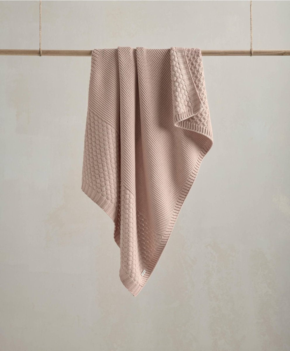 Seedling knitted blanket in dusty pink with textured waffle knit, folded and draped