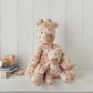 Small plush giraffe toy sitting on a shelf, beige fur with brown spots