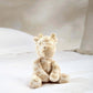 Small plush giraffe toy with soft beige fur and brown spots, sitting pose