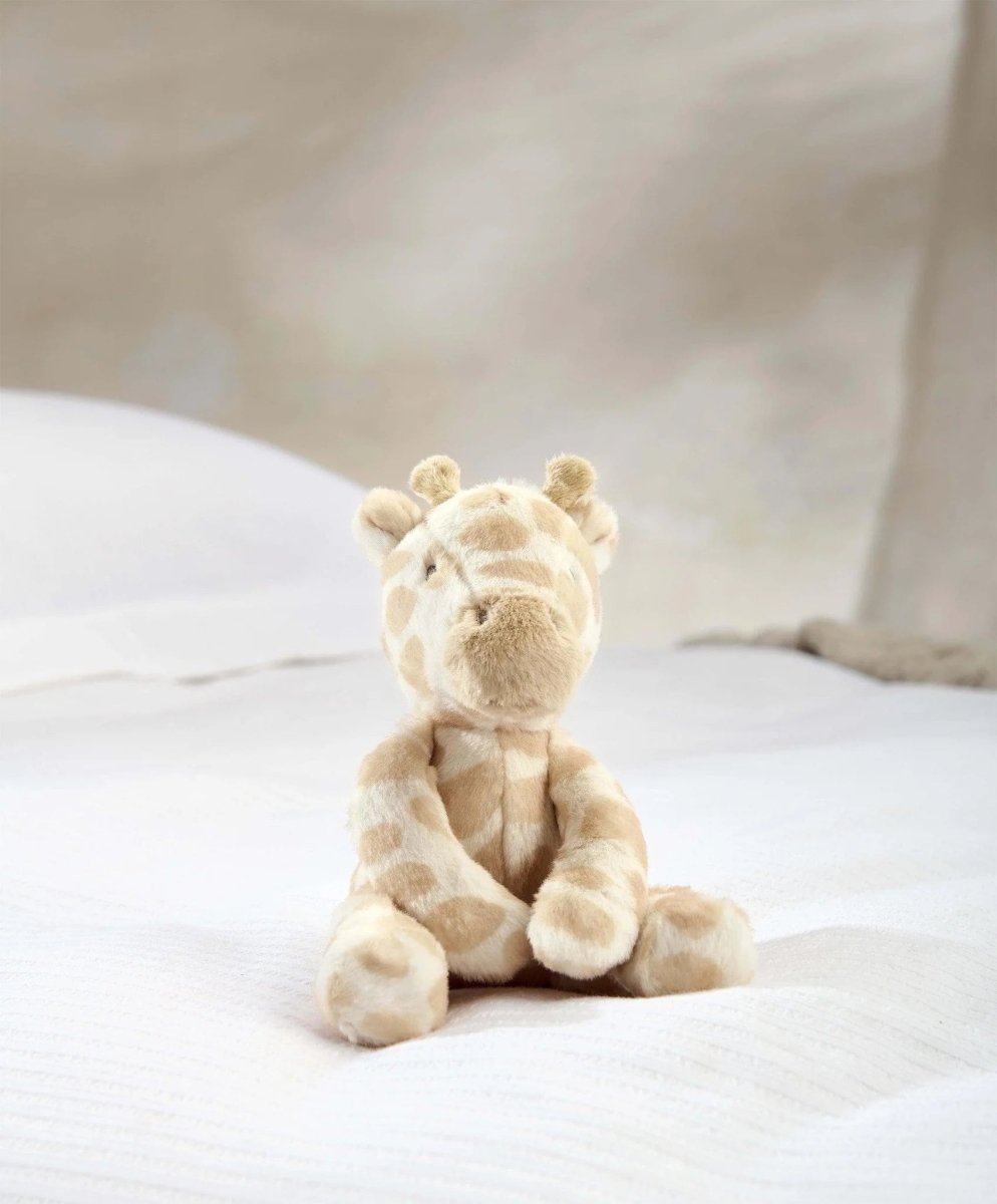 Small plush giraffe toy with soft beige fur and brown spots, sitting pose