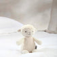 Lamb soft toy plush with beige fleece and stitched eyes, standing on white fabric