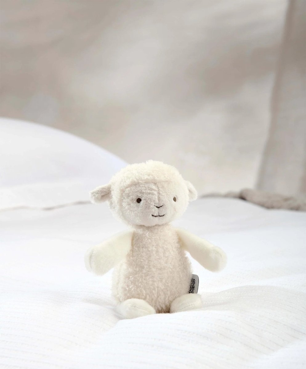 Lamb soft toy plush with beige fleece and stitched eyes, standing on white fabric