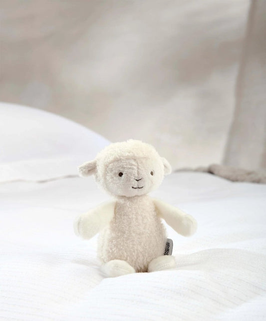 Lamb soft toy plush with beige fleece and stitched eyes, standing on white fabric