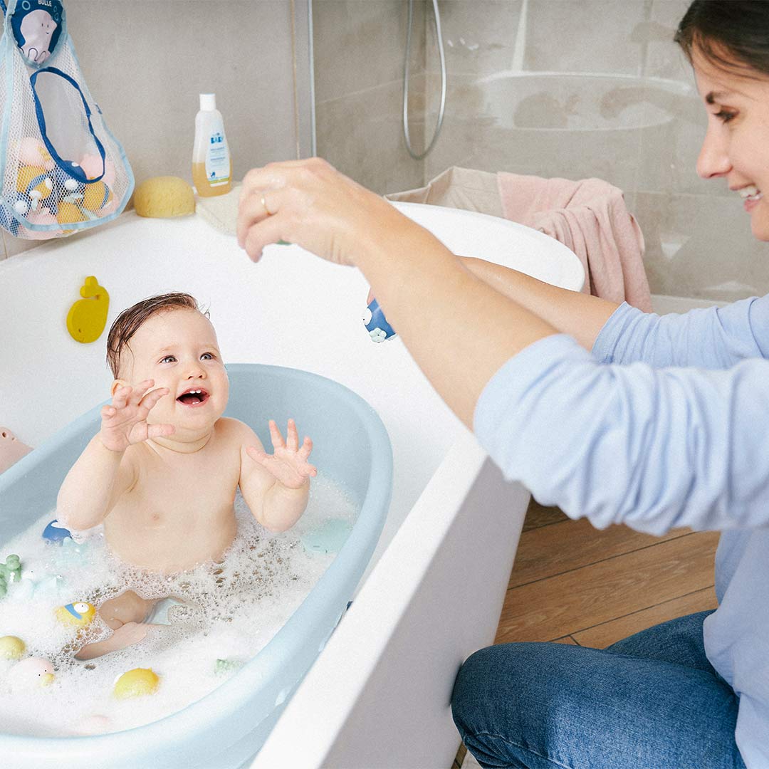 Light blue baby bath tub on stand filled with water