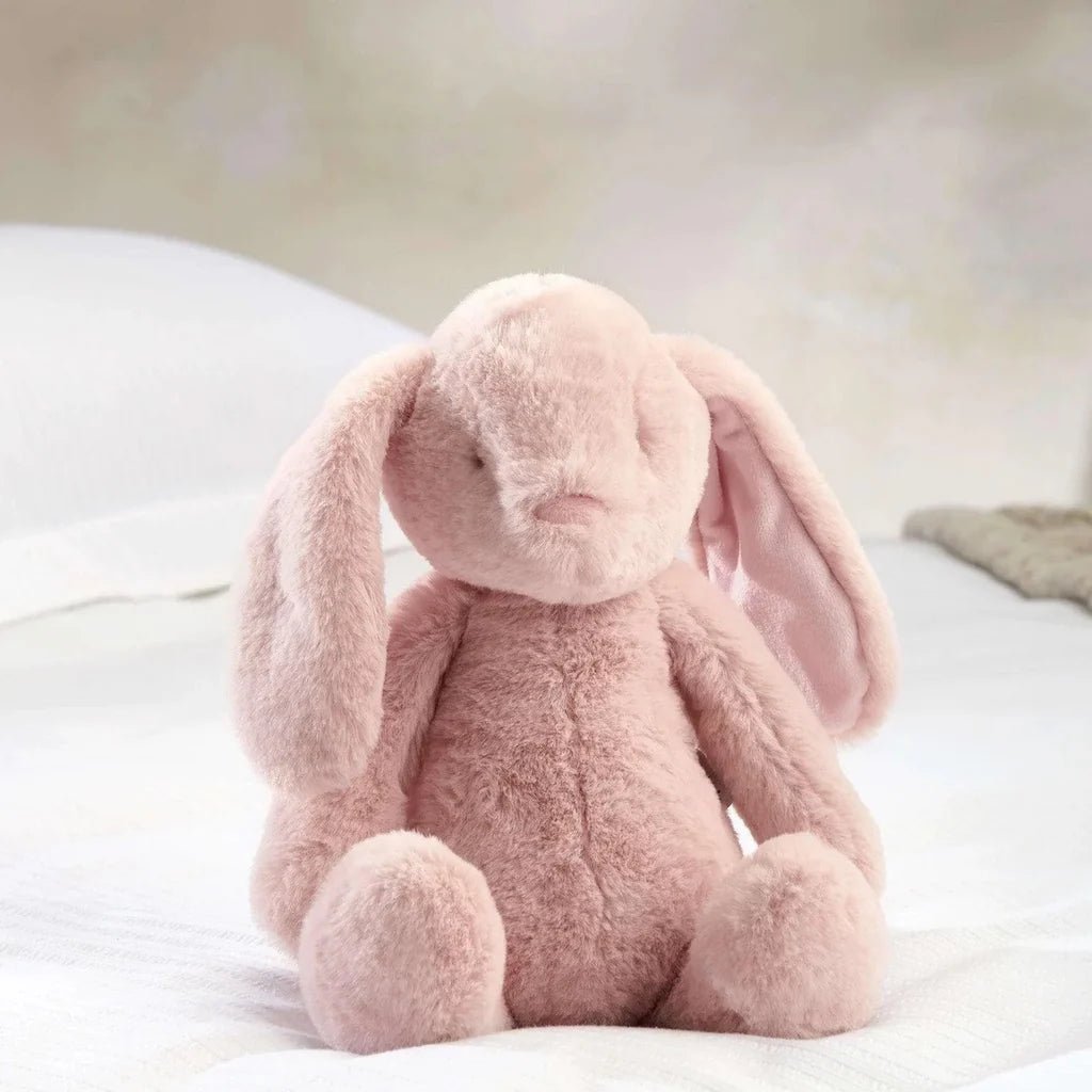 Light pink plush bunny soft toy, side view with floppy ears and small nose.