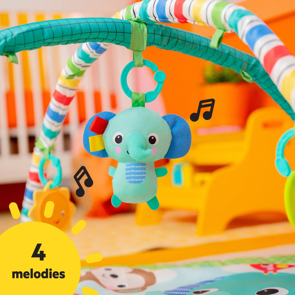 Plush elephant dangling from striped arch on green baby play mat