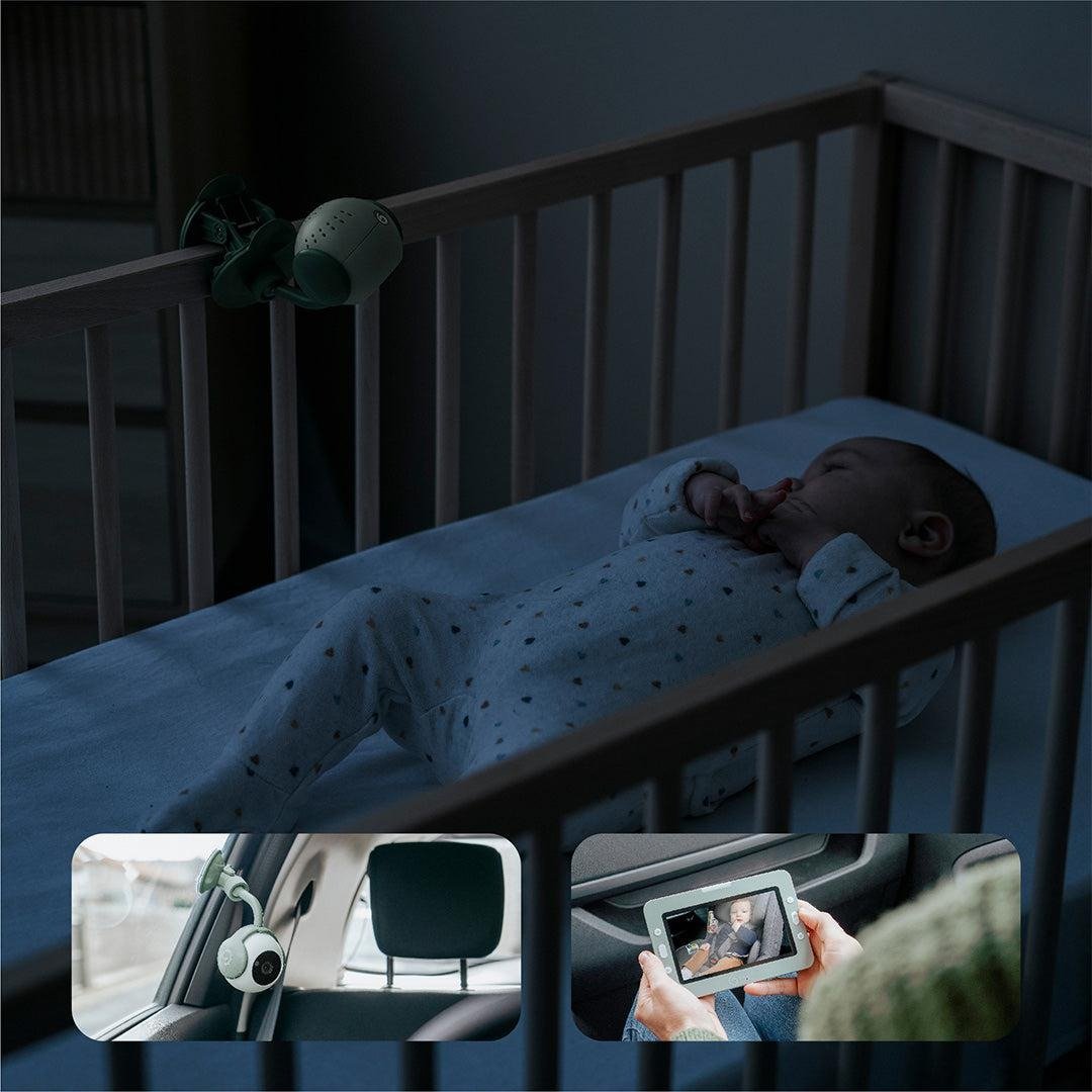 Portable baby monitor showing baby in crib on a small screen preview