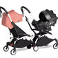 Two-seat stroller with pink carrycot and black seat, side-by-side wheelbase
