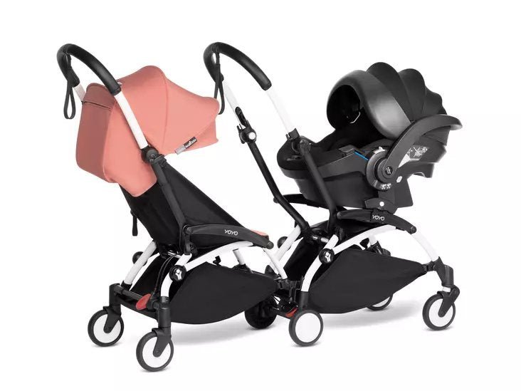 Two-seat stroller with pink carrycot and black seat, side-by-side wheelbase