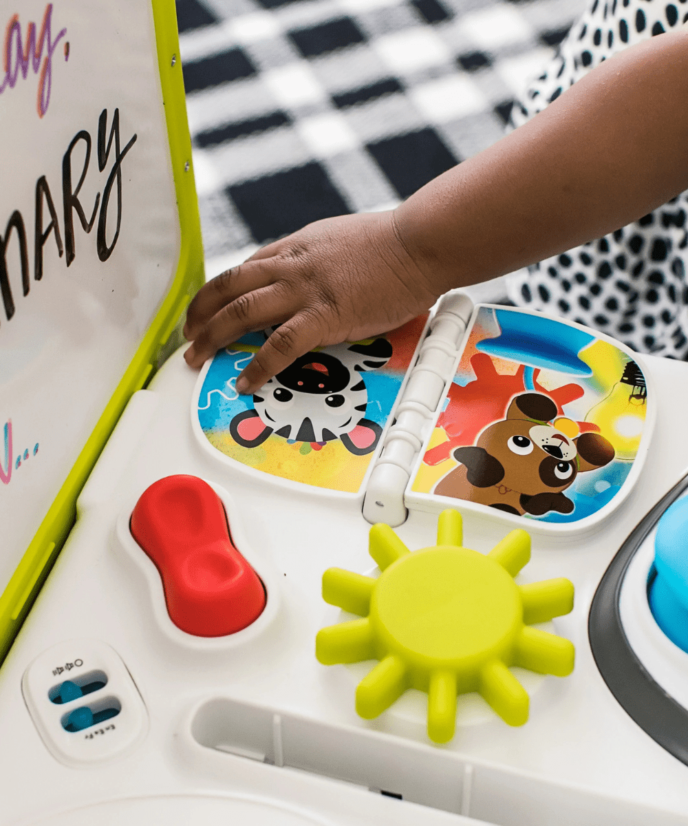 Hands playing the activity table with red crank, yellow gear, and cow-shaped cover