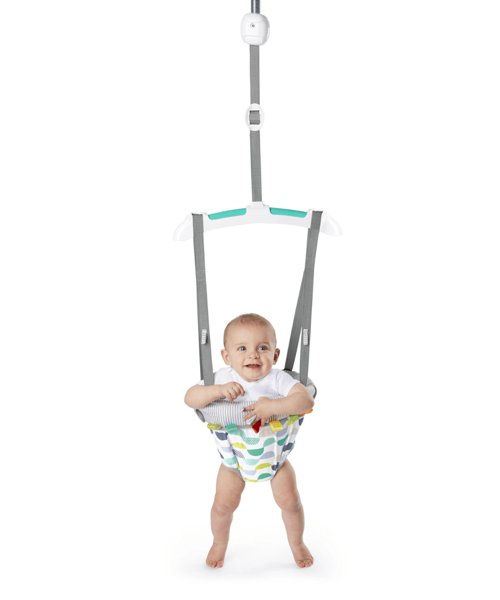 Door jumper seat with baby in white tee, gray striped harness, holding on overhead strap