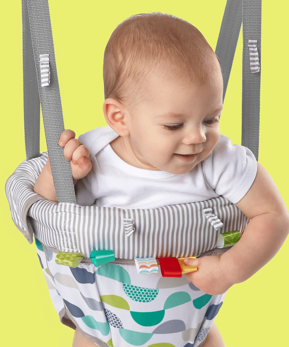 Door jumper seat with baby wearing white top, gray striped safety harness and patterned fabric