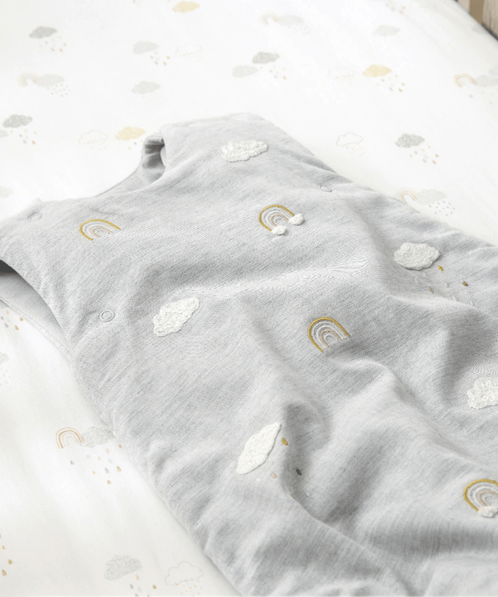 Grey baby sheet set with cloud and rainbow pattern, folded for display