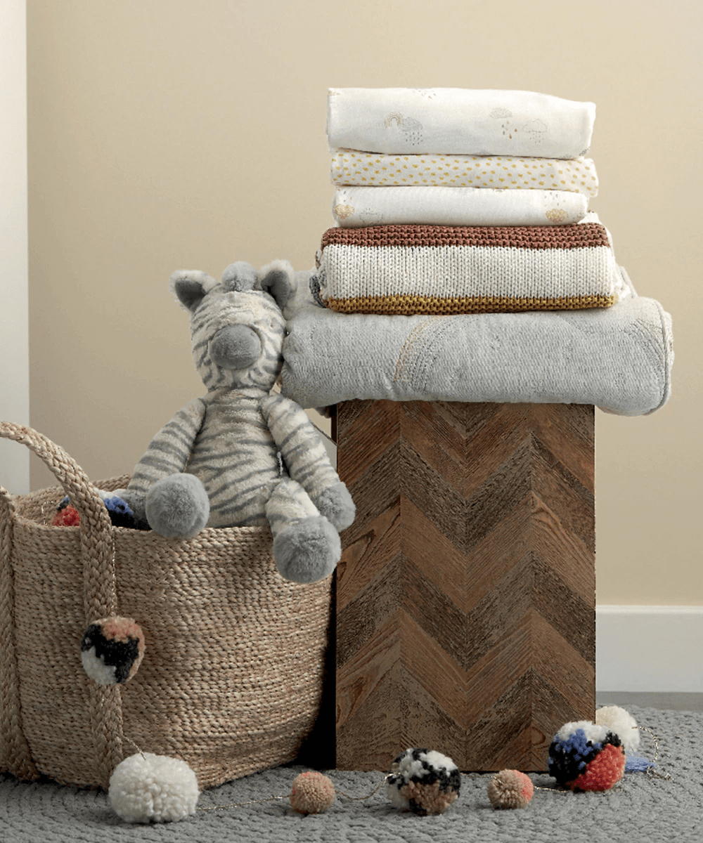 Stack of folded sheets with small rainbow and cloud designs in light colors